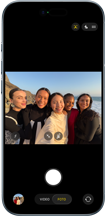 iPhone Air, frente, la pantalla muestra la cámara frontal Center Stage abierta con una selfie grupal de cinco personas centradas en el encuadre